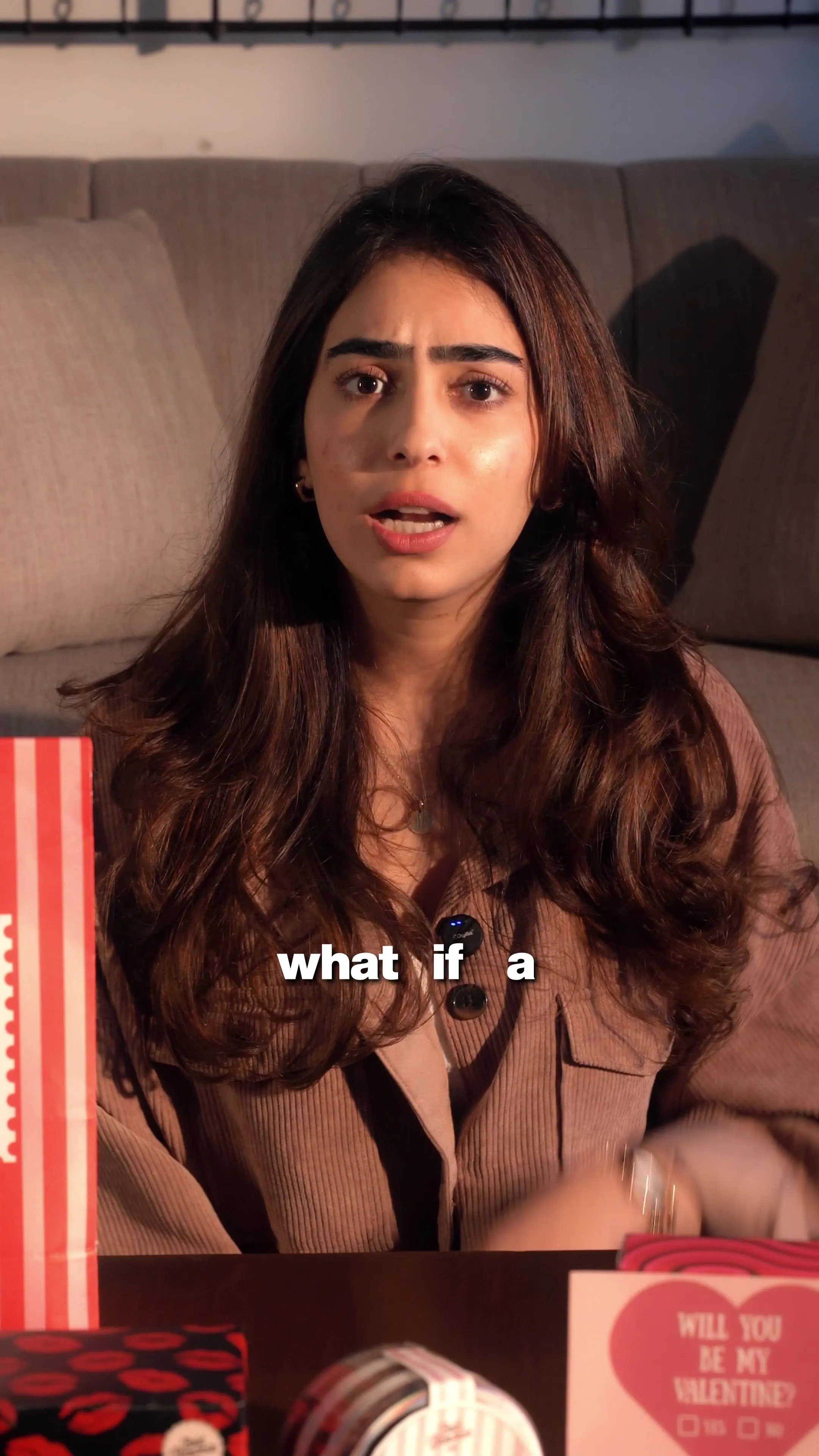 A woman sitting on a couch beside a red-and-white striped gift box, captioned "what if a."