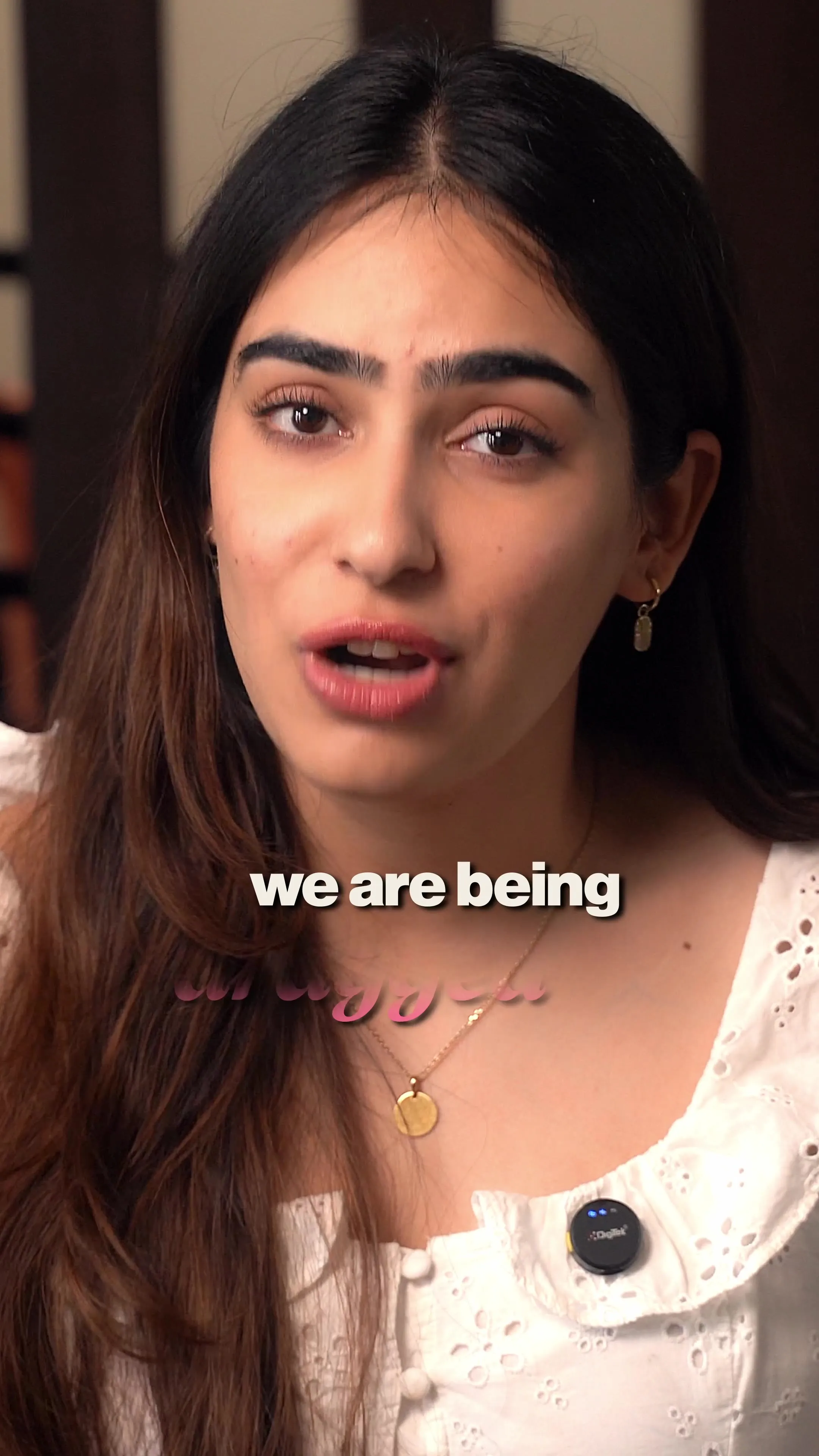 A close-up of a woman mid-sentence, captioned "we are being."