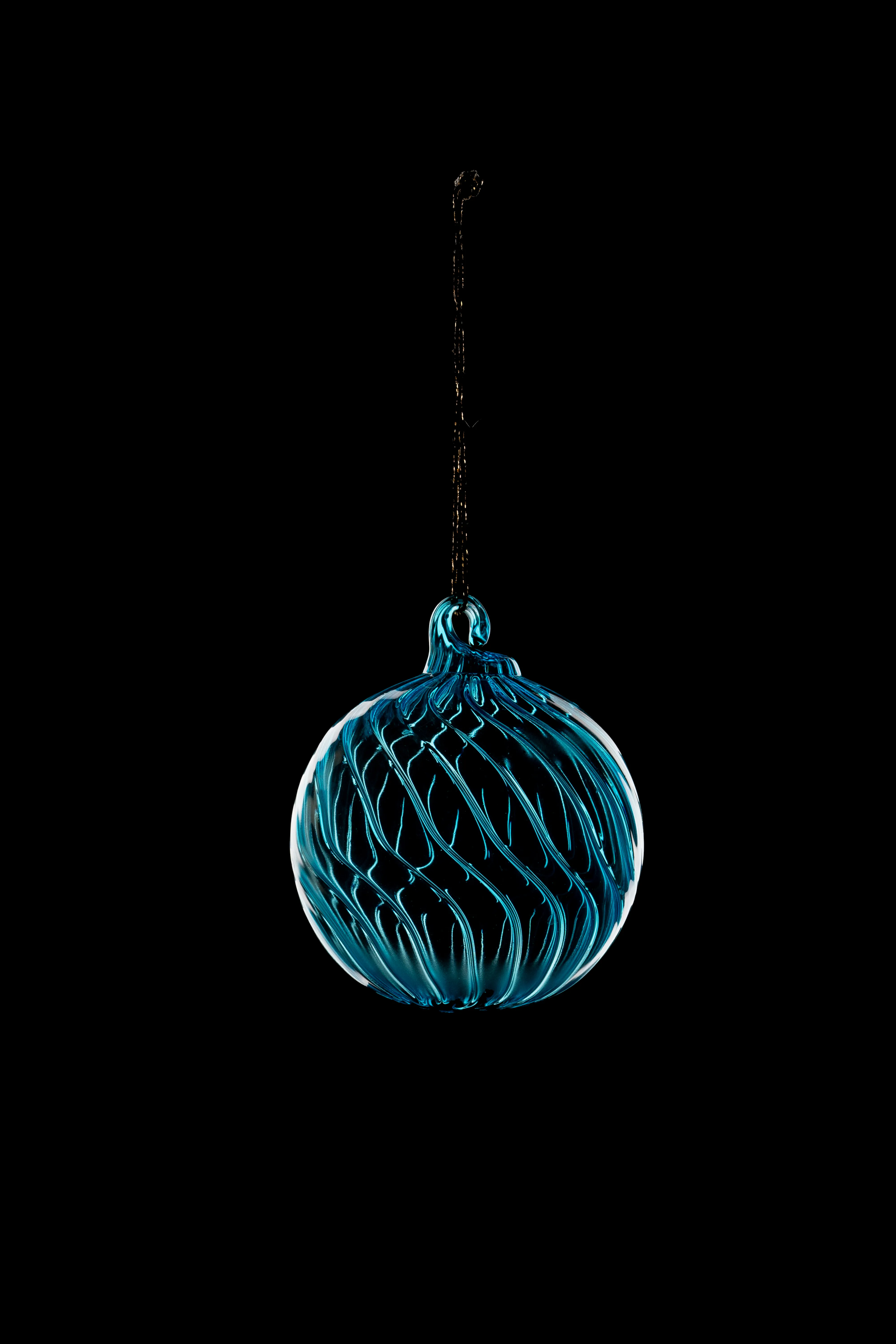 A teal swirl-textured glass ball ornament hanging against a black background.