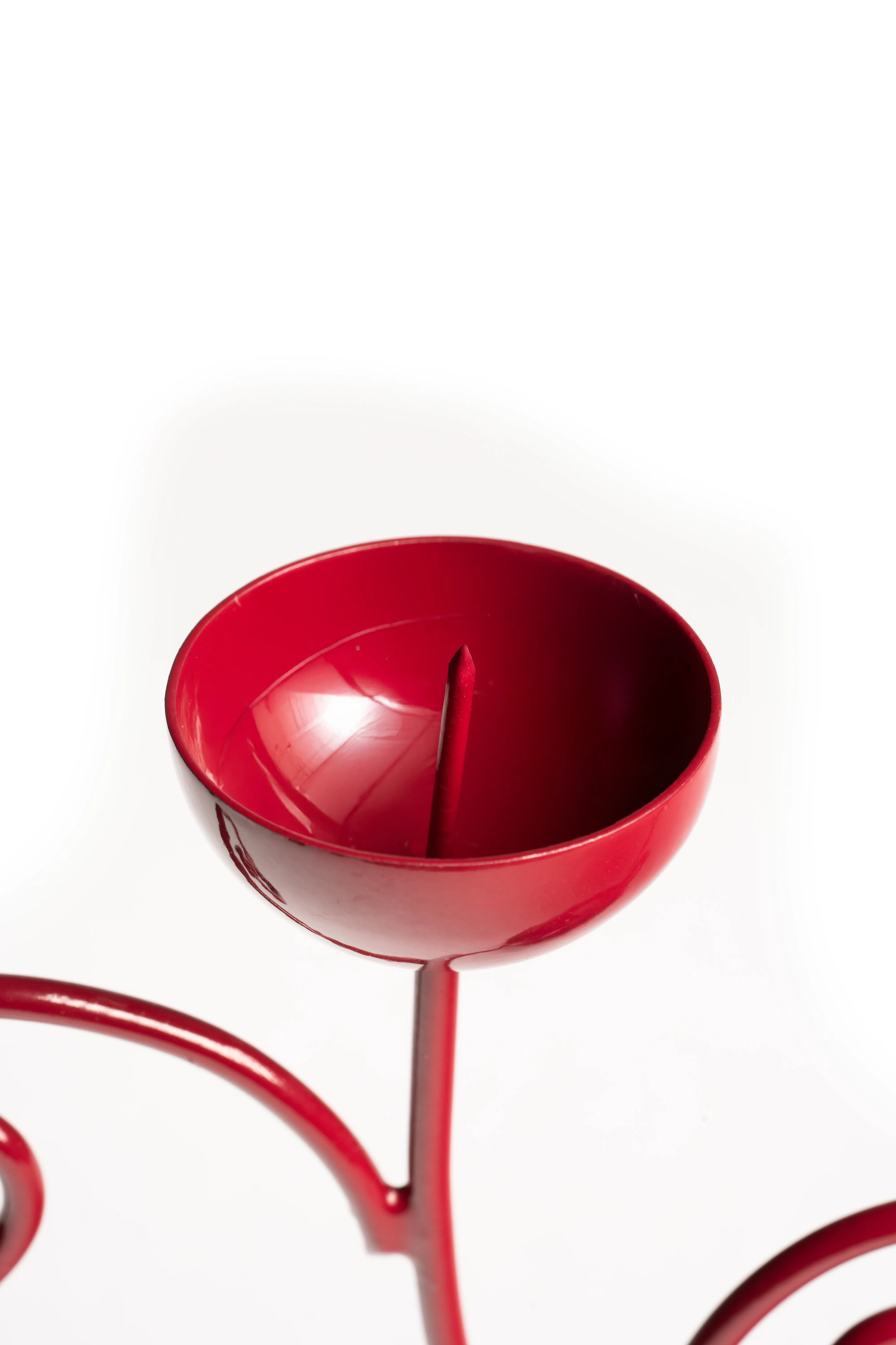 A top-down close-up looking into the red double candle holder's cup against a white background.