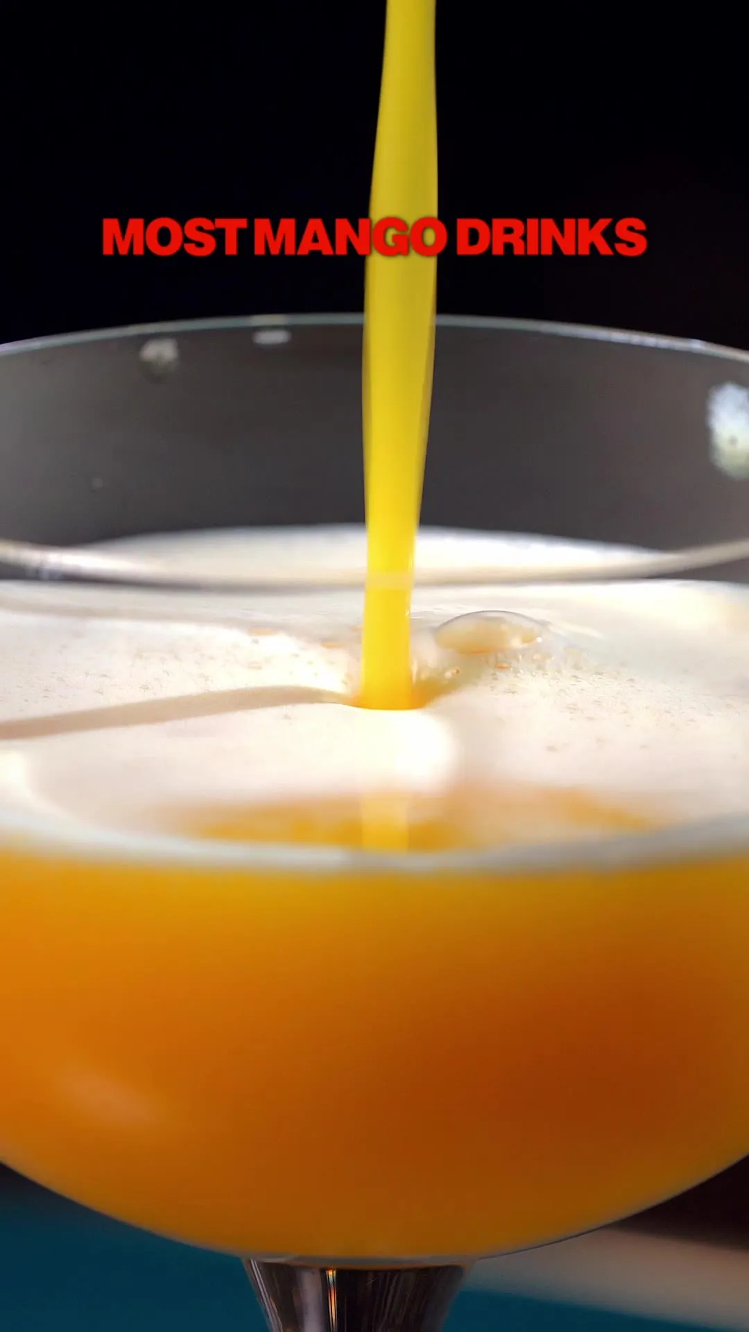 An orange mango cocktail being poured with a frothy top.
