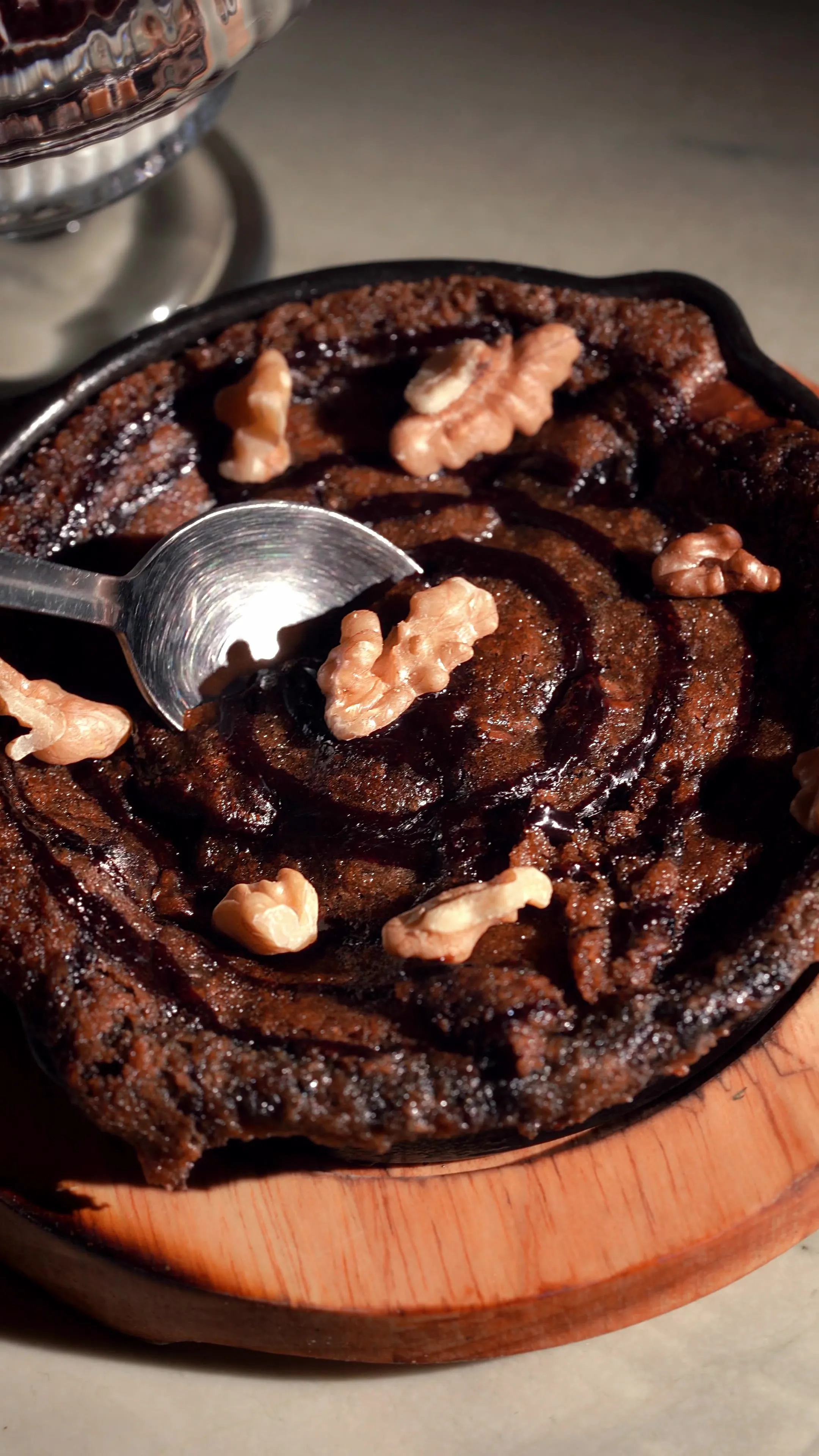 A spoon lifting into a warm walnut skillet cookie dessert.