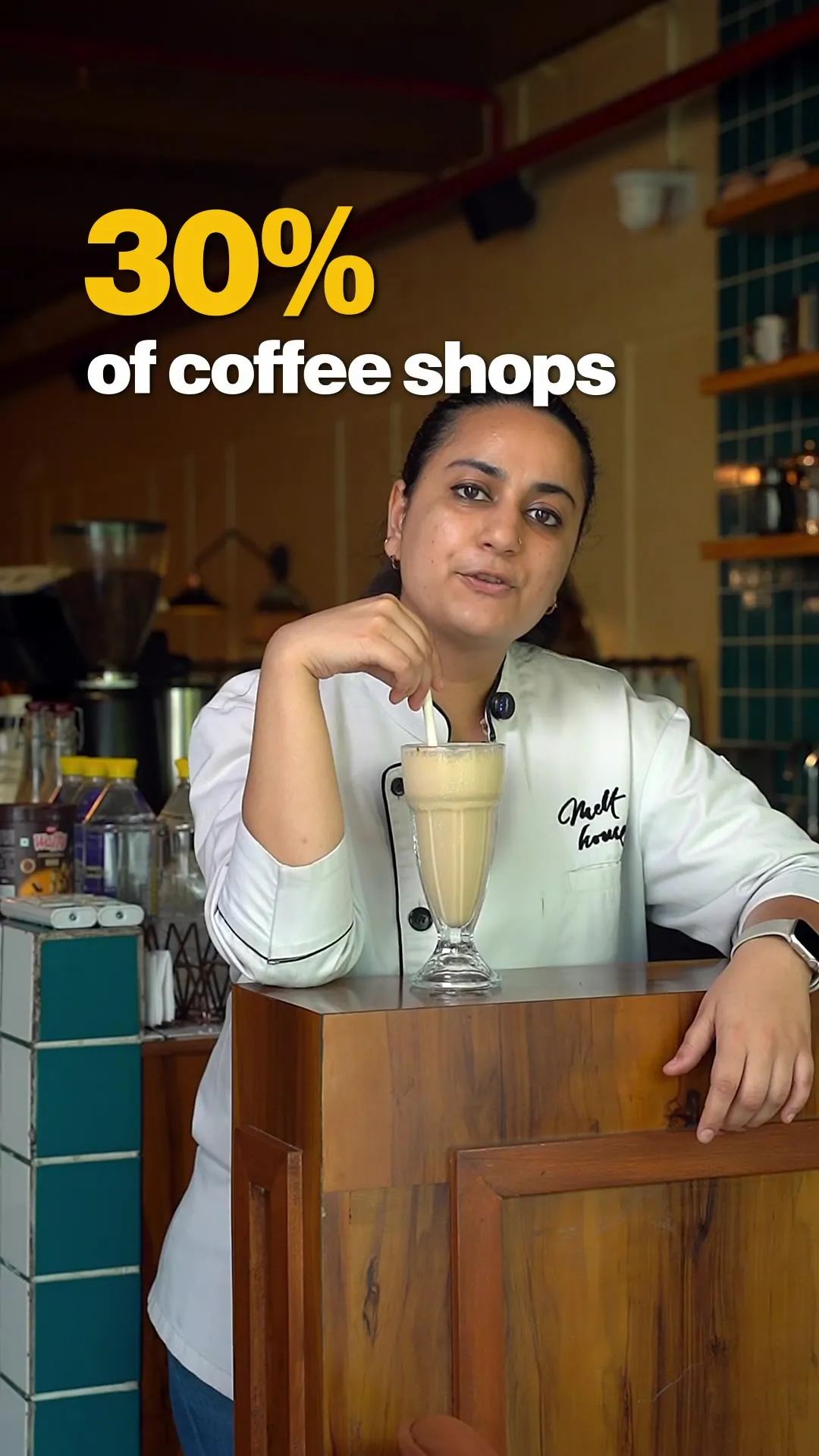 A staff member leaning on the counter beside a tall cold coffee, captioned "of coffee shops."