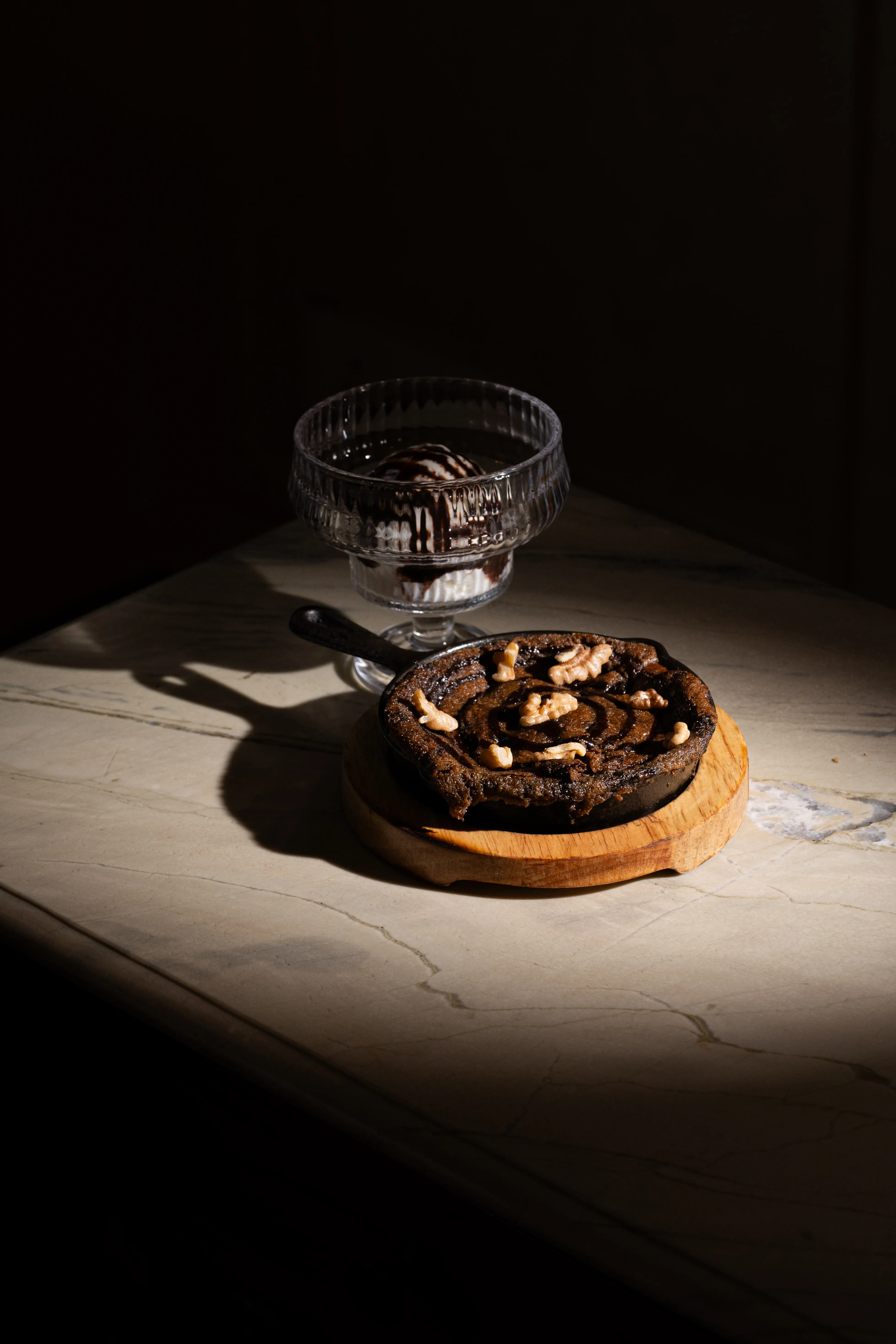 A closer view of the walnut skillet dessert and sundae glass in dramatic side lighting.