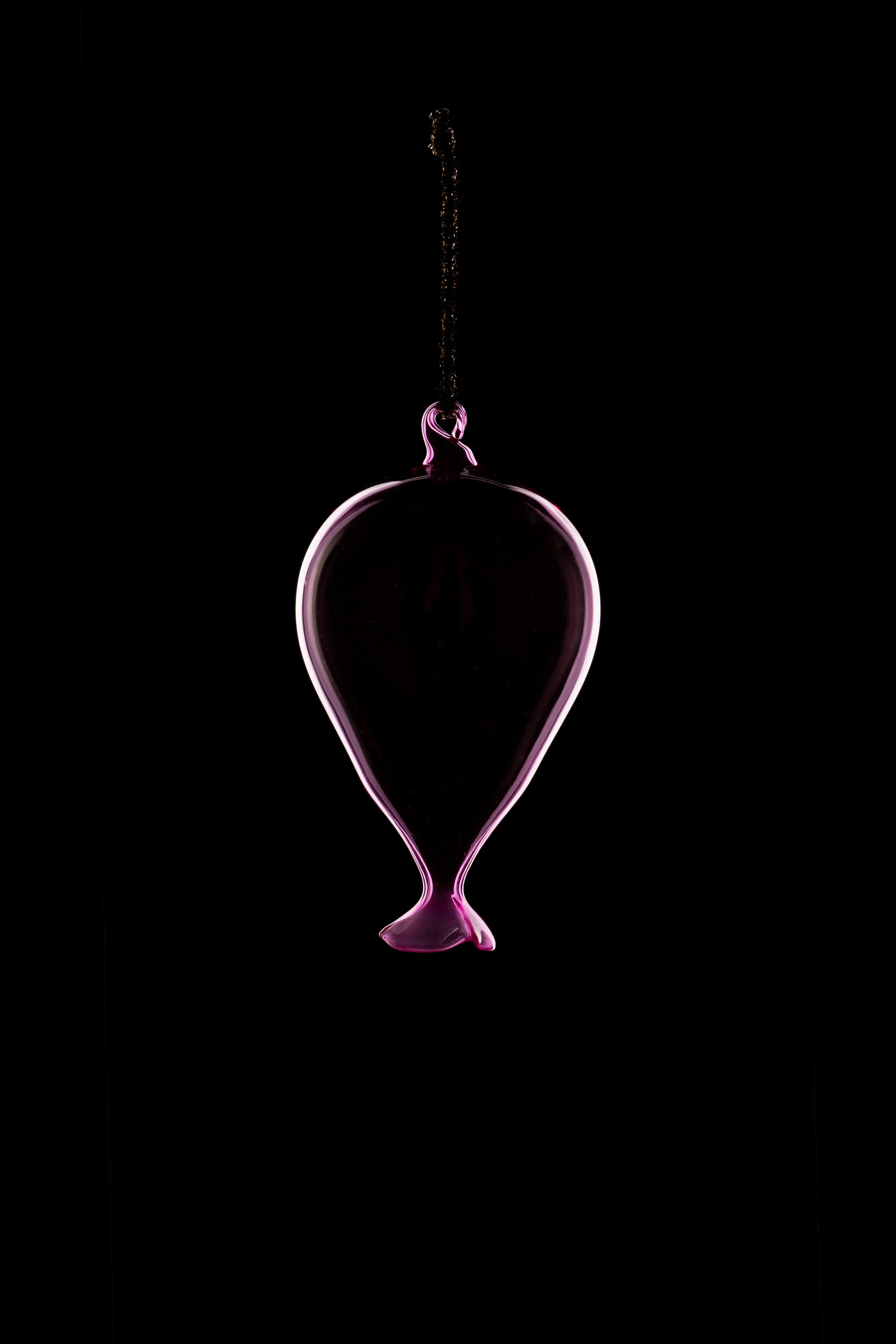 A pink glass balloon-shaped ornament on a black cord, hanging against a black background.