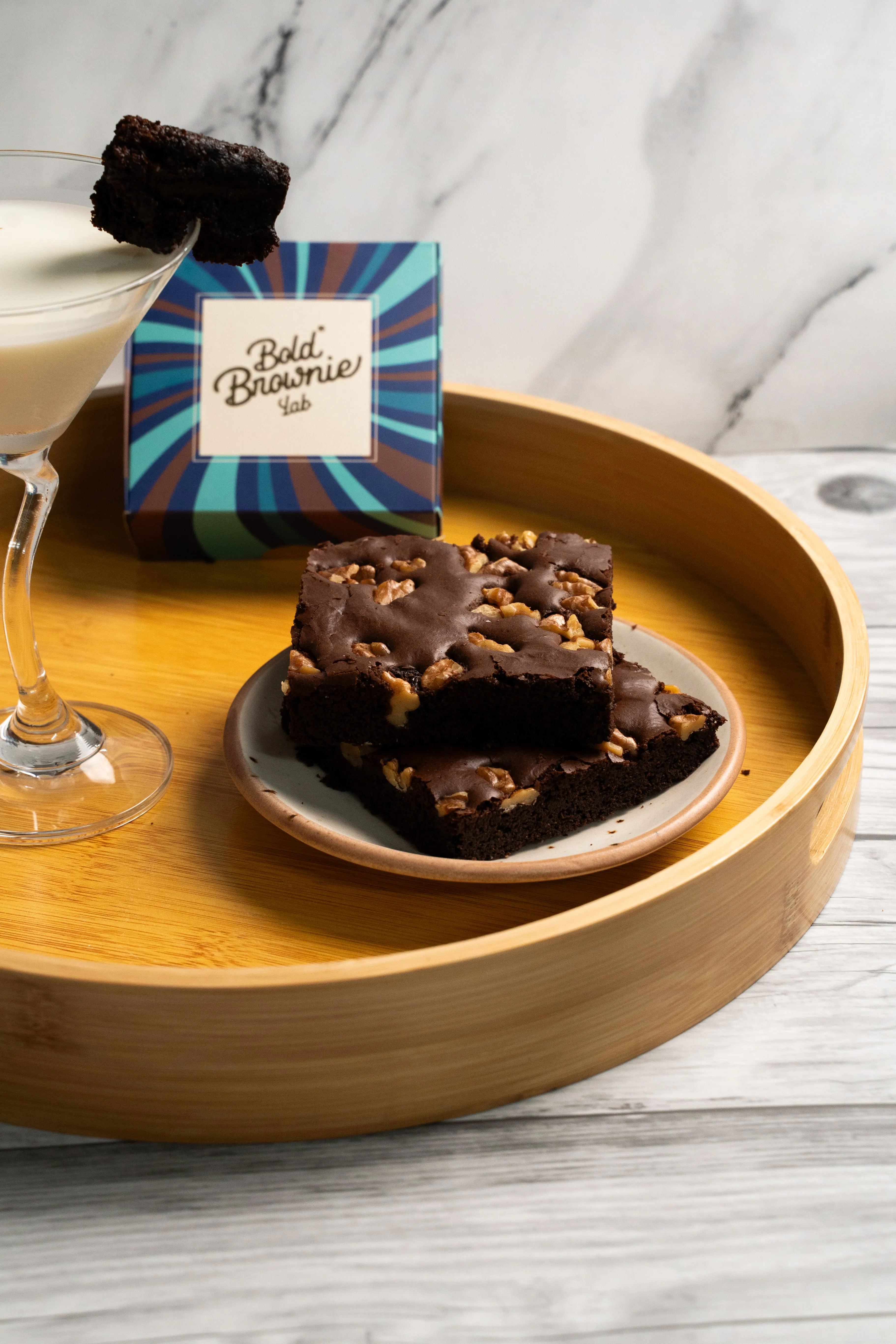A closer view of the cocktail, brownie garnish, box, and plated walnut brownies.