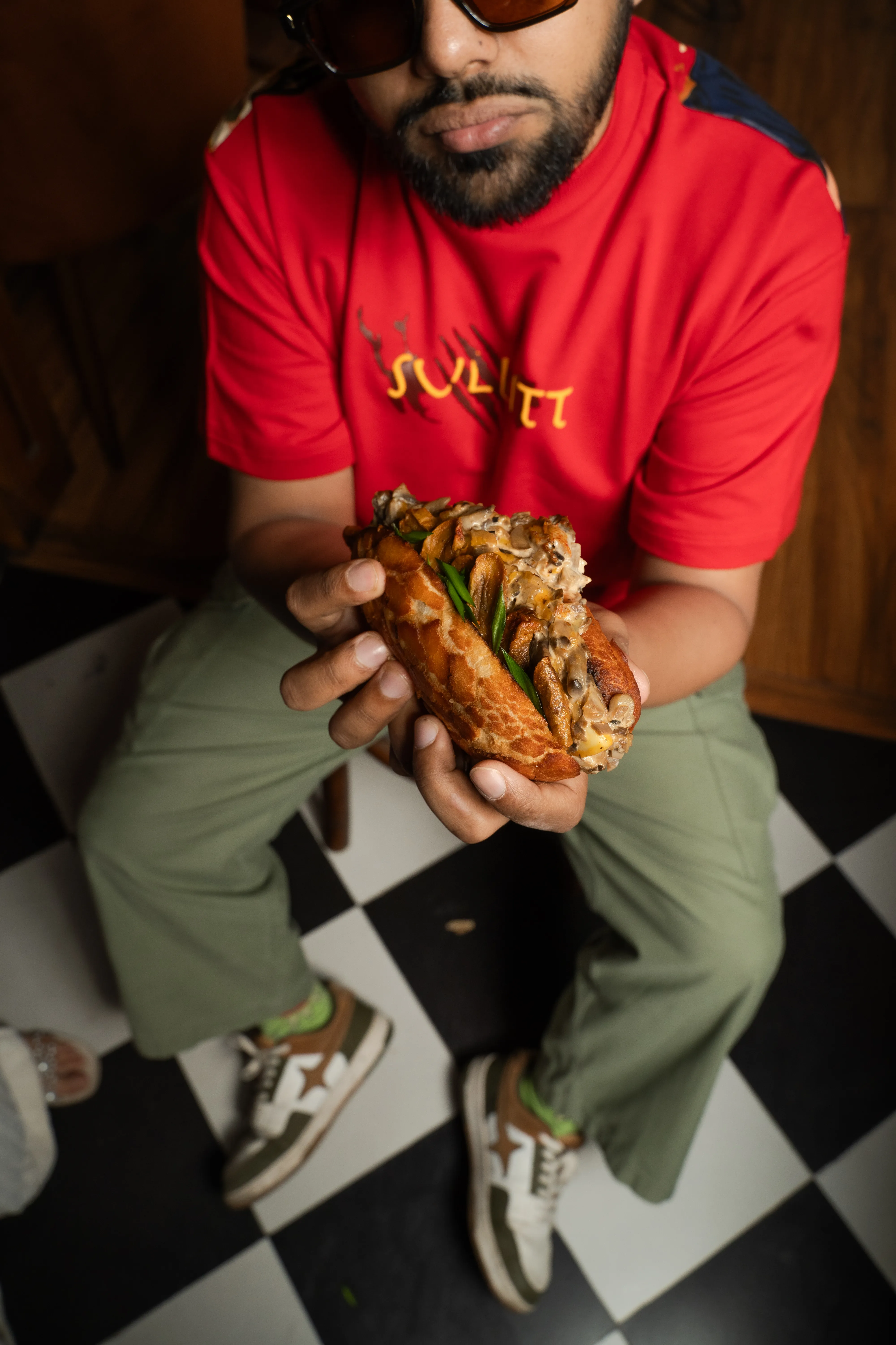 A close-up of the man offering the mushroom bao sandwich to the camera.