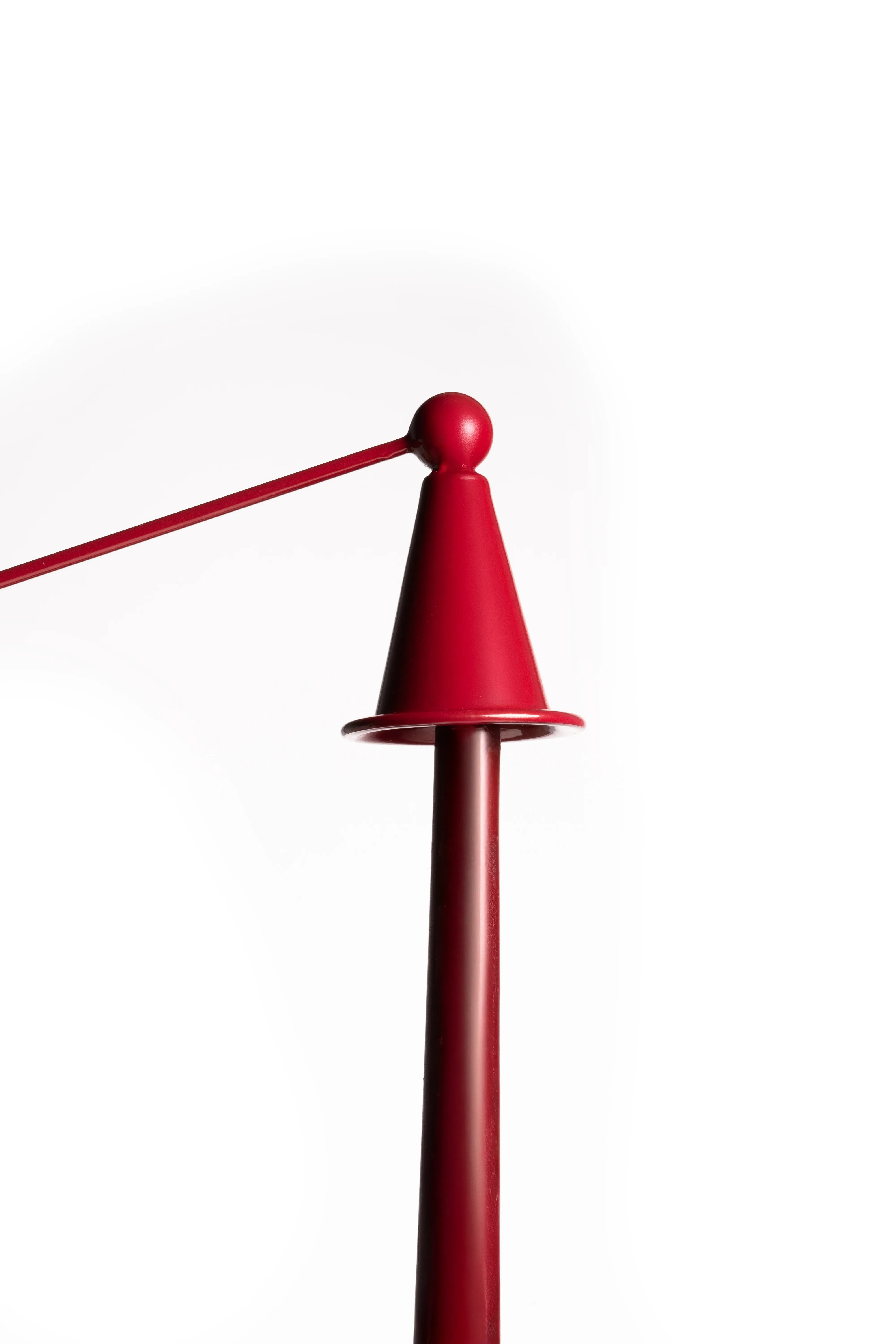 A close-up of the red candle snuffer's cone and handle against a white background.
