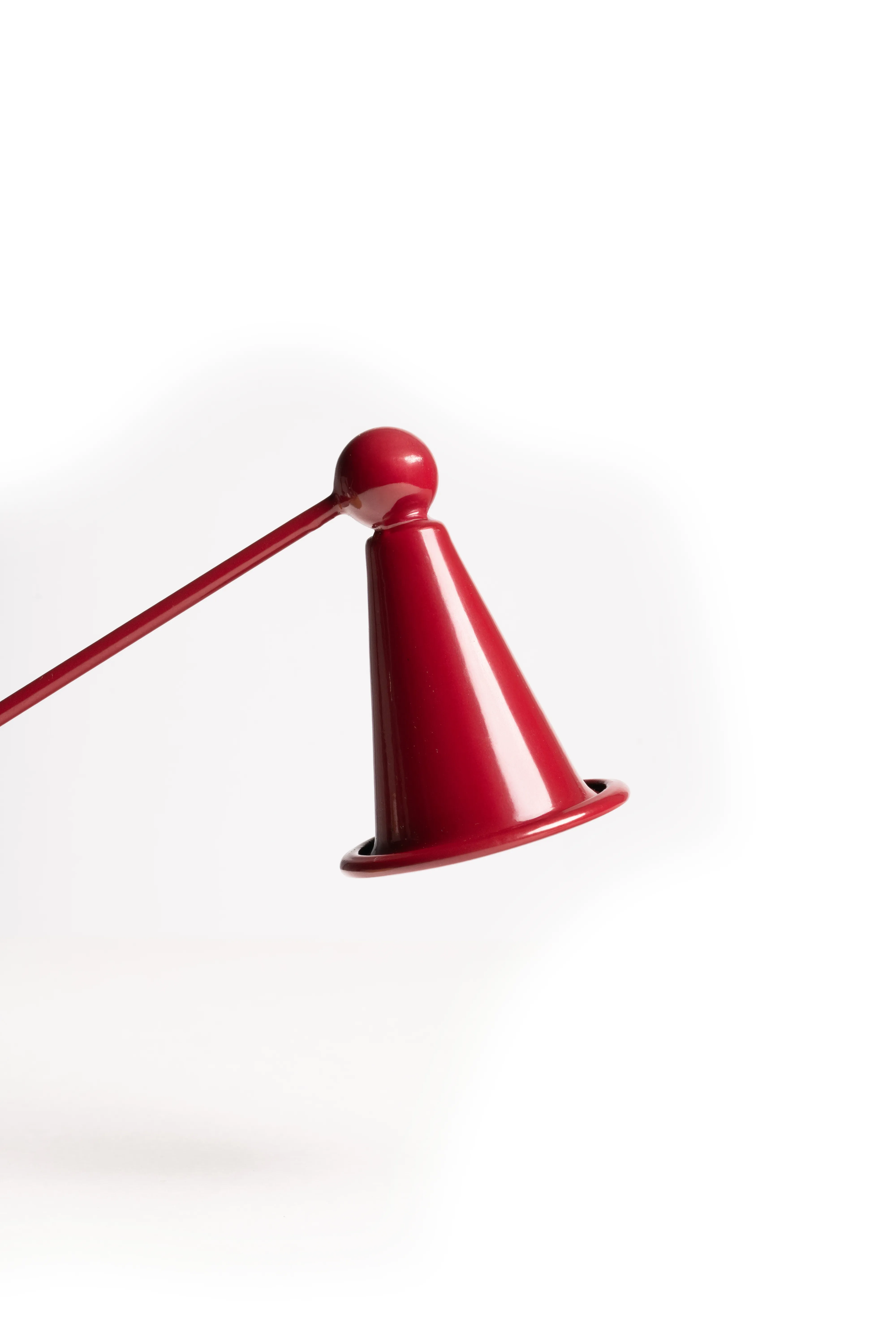 A close-up of the red candle snuffer's cone tip against a white background.